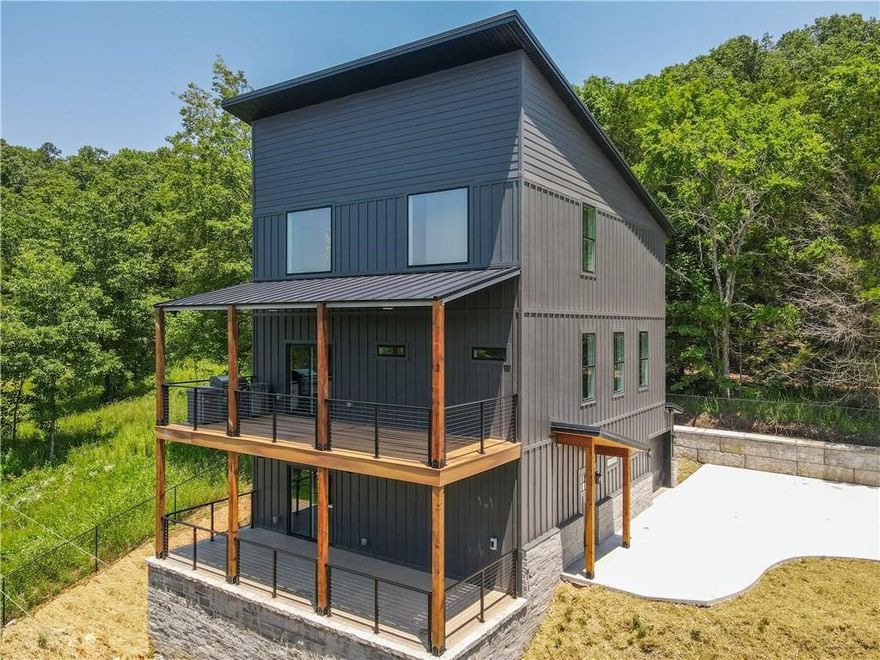 Exquisite New Home on Beaver Lake with Boat Slip! Nestled near Hogscald and Lovers Leap in Eureka Springs, this stunning 3-story, 3,119 sqft. home sits on 0.487 acres and includes a private boat slip at the community dock. The main level features a spacious bonus room, 1-car garage, laundry room, mud room, full bath, and large outdoor deck. The second floor offers a gourmet kitchen with quartz countertops, living room, two bedrooms, full bath, and an expansive deck with built-in grill and breathtaking views. The top floor boasts a luxurious master suite with his-and-hers closets, tile and stone walk-in shower, and a large storage room with access to the HVAC system. Built for comfort and efficiency, the home’s exterior walls are insulated with 6-inch thick spray foam for maximum energy savings. The exterior combines natural stone and Hardie cement board, topped with a durable H-Loc metal roof. Plus, 4 exterior security cameras provide peace of mind. Schedule a showing today!