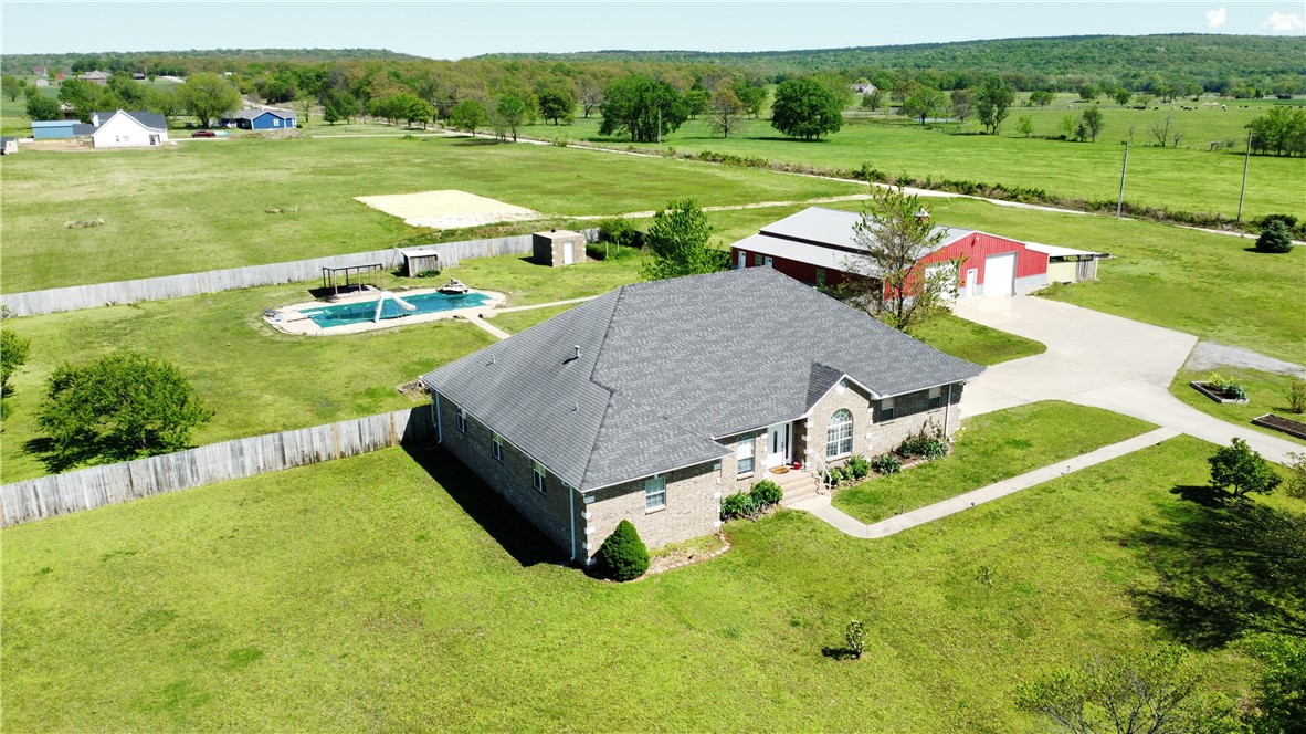 Beautiful brick home on 5.7 acres, minutes from town! Enter the estate on the concrete drive that will direct you to the shop or the home while passing by several of the trees recently planted, varieties include pecan, apple, peach, & plum. 3 bds, 3.5 ba, 3144sf-each bedroom has a bath! Large office with built-ins, a music/game room or 2nd office, additional living area or 4th bedroom. Semi-open floor plan, split bedrooms. Kitchen has granite, island workspace, gas range & double wall ovens for the cook in the family. Huge pantry with access directly from garage. Sewing room off utility. Bedrooms are oversized w/ walk in closets. Hand scraped hardwood/tile flooring. 60x60 shop w/ 2 overhead doors, 20x25 lean-to and 1200sf 1 bedroom/1bath apartment w/ utility area, LR, kitchen. In-ground saltwater pool/vinyl liner in the privacy fenced yard. Brick 10x16 storm shelter w/ electric. A short drive to everything-17 mi from U of A, 9 mi from 412/shopping/bank in Siloam Springs, 15 mi to I49. Pool-Vinyl liner-3yr/cover-1yr