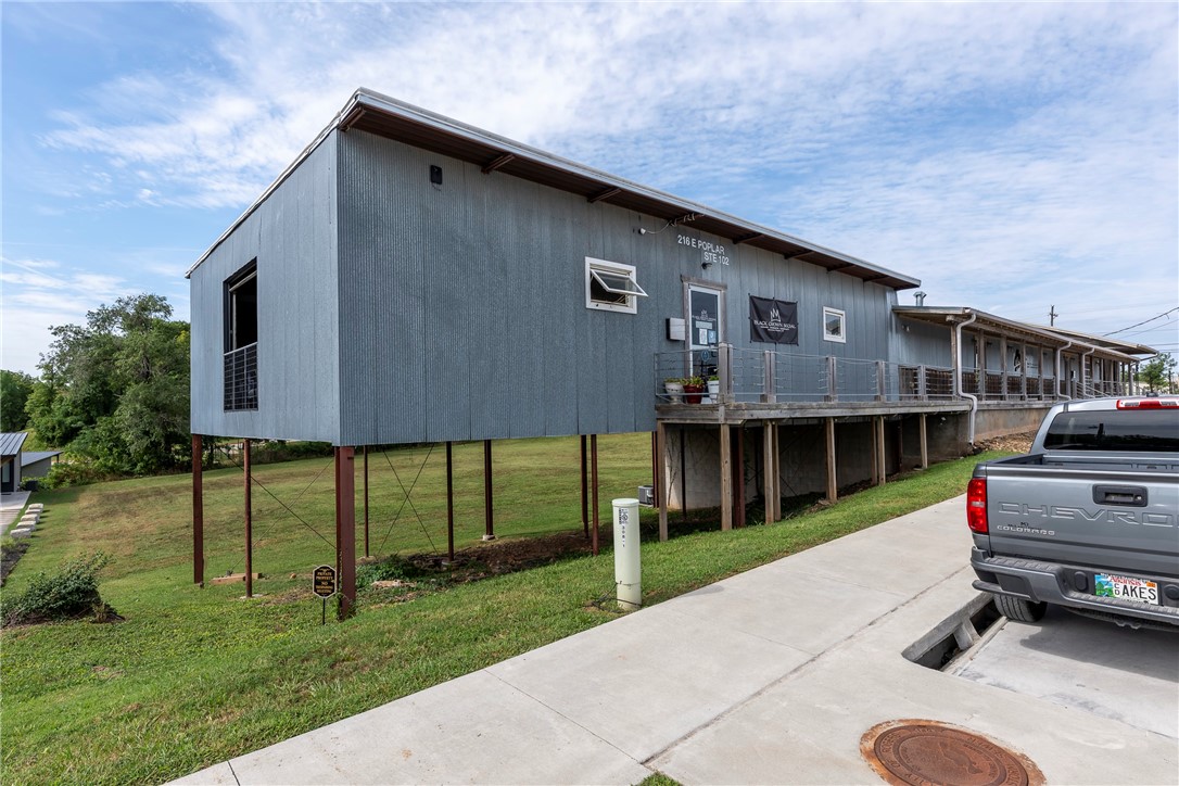 The space is located across from The Railyard and adjacent to the Razorback Greenway bike trail, offering excellent visibility and accessibility. The current build-out could be used for a yoga and spin studio, retail space, office space, exhibit area and has two large glass garage doors, a modern black ceiling with upgraded lighting, and two restrooms. The open floorplan allows for flexible uses, along with the Zoning of T5.2, this location supports a wide range of commercial uses. Showings will be scheduled once the current tenant has vacated.