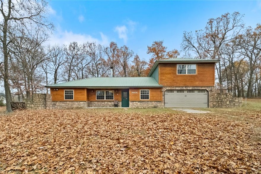 Enjoy peaceful county living while still being only 20 minutes from downtown Bentonville. Just 3 miles outside Centerton and nestled in the privacy of mature hardwoods, this 3 bedroom 3 bath 1,892 sqft home sits on the back half of 5 beautiful acres consisting of pasture and wooded areas. A two sided, stone wrapped fireplace centered between the living and dining areas catches your eye as you walk in the front door. Knotty pine cabinets, stainless steel appliances, and ample granite counter top space bring out the charm of the kitchen. Located above the garage, the large primary suite offers privacy inside as well as outside with access to its own private deck off the back of the home. Large secondary bedrooms help set this home apart from others. This one is perfect as it is, while having all the possibilities of making it yours.