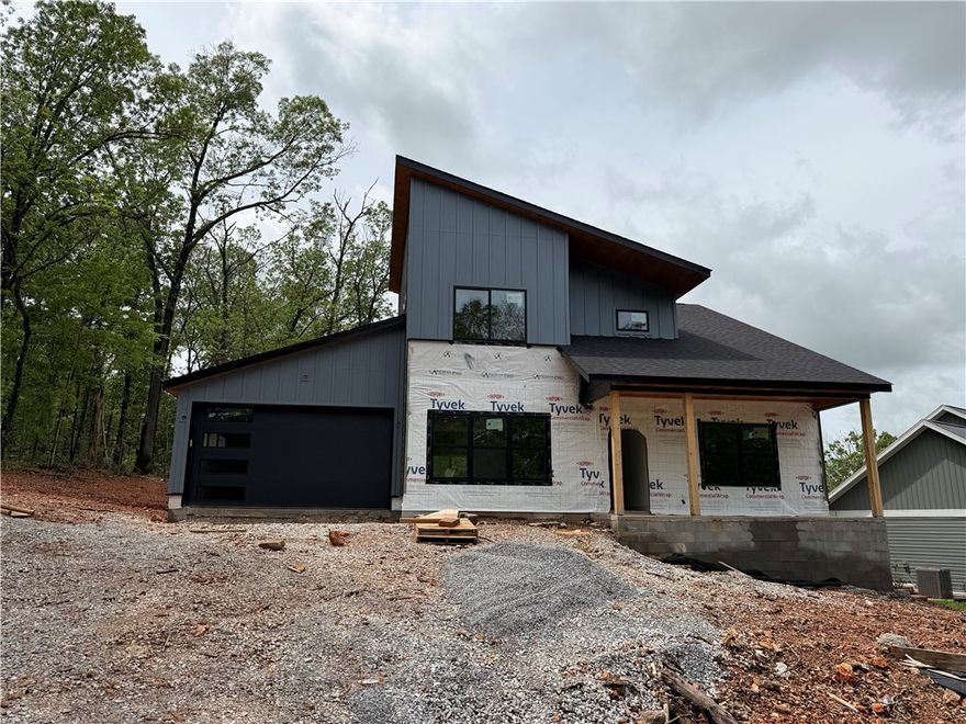 Discover this exquisite new construction in Bella Vista featuring full POA amenities! The modern yet minimalist design showcases white oak cabinets, matte black fixtures and hardware, and quartz countertops throughout. Enjoy two spacious bedrooms with huge walk-in closets, a dedicated office, and 2.5 stylish baths. The versatile floor plan offers two living areas.  The main floor is anchored by an electric fireplace with custom built-ins, while the kitchen's massive island creates a perfect gathering space. Indoor-outdoor living comes easy with both an upstairs balcony and main floor deck, and the timeless exterior combines brick with concrete batten board siding. This thoughtfully designed home balances contemporary style with natural elements, creating an inviting space that's both sophisticated and comfortable - all just steps to Bella Vista's incredible trail systems with easy access to Bella Vista's complete range of amenities.