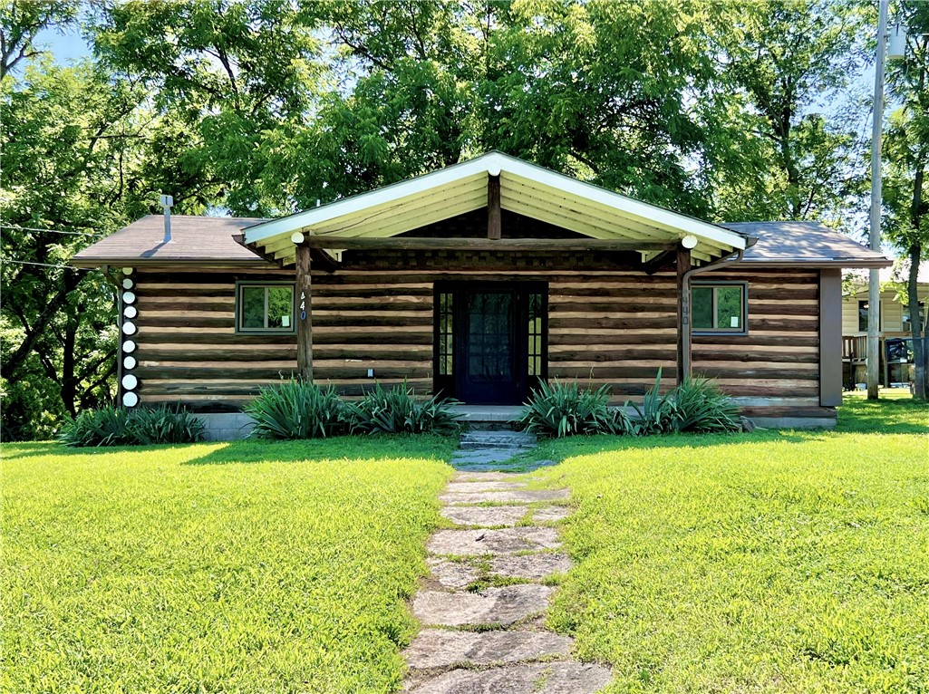 Rustic log cabin charm with all the modern amenities! Spacious, open concept living room & kitchen, one bedroom and one bathroom. Beautiful, traditional log construction, hardwood floors throughout, brand new windows and fresh interior paint. The huge covered front porch is just begging for a couple of rocking chairs, and is the perfect place to sit with your morning coffee or unwind after a busy day. Expansive pasture views and mature trees add to the peaceful, country living feel. Ample space to garden, if desired. City utilities (water, electric, gas). Located right off of Hwy 59, just 5 miles to both Gravette and Noel, Mo, 11 miles to I-49, and approximately 20 miles to Bentonville, Centerton, and Bella Vista. Less than half a mile away is Sulphur Springs City Park, a popular spot for swimming and fishing in the cool, spring fed Lake La Balladine and Butler Creek - perfect for summer!