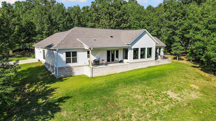 Set on 5 acres, this 1-story 2022 build blends everyday comfort w/ sophisticated design. Featuring 3 beds, 2.5 baths & an office, the thoughtful split floor plan balances open-concept living w/ privacy, while an oversized entryway welcomes you into the sun-filled living spaces. Large windows throughout flood the home w/ natural light, accentuating the modern finishes. At the heart of the home is the kitchen, complete w/ a 10’ island w/ bar seating, walk-in pantry, SS appliances & a 6-burner gas cooktop. A dry bar enhances the dining area, while french doors open to a covered patio, perfect for entertaining. The living room features vaulted ceilings, a gas fireplace & a custom oak mantle. The primary suite is a true retreat w/ a private patio. The ensuite bath features a soaking tub, walk-in shower, dual vanity, & generous walk-in closet. With private lake access & a sandbar, 2 patios for year-round enjoyment of breathtaking views, this home perfectly blends luxury and functionality in a serene lakeside setting.