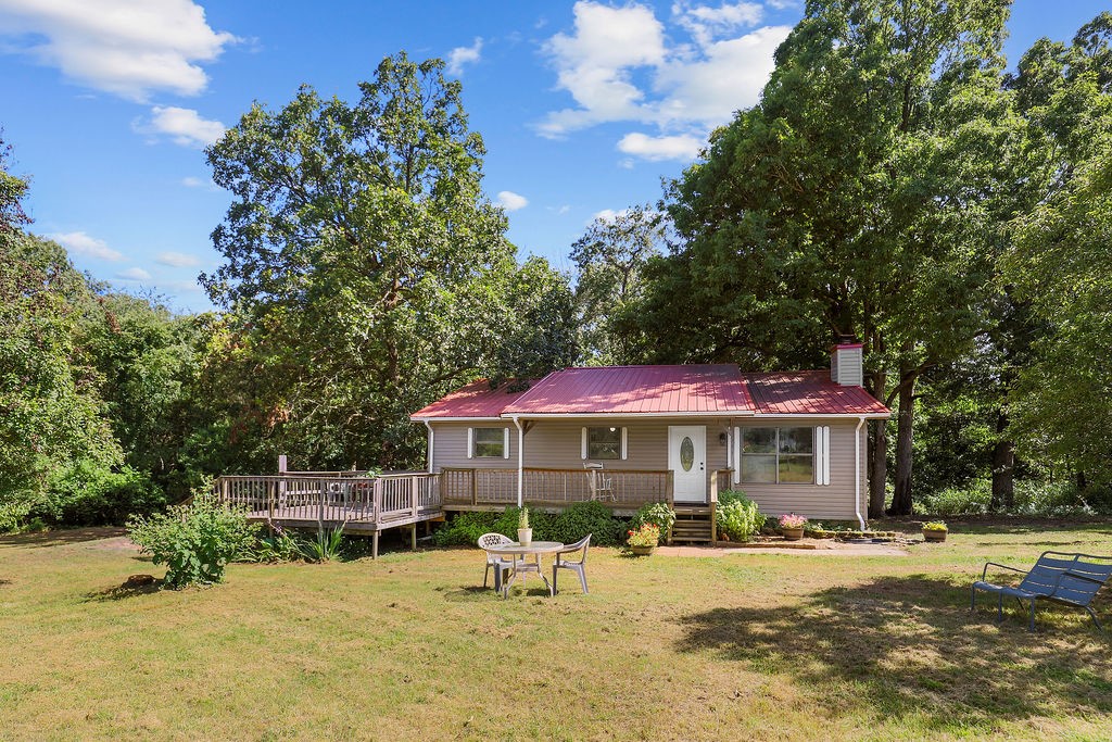 This charming country home sits on expansive acreage extending down into a scenic ravine with mature trees. The property includes a large garage/shop with newly replaced asphalt shingle roof as well as a stone patio with fire pit and a fenced garden area. Inside, you'll find 3 bedrooms and 2 full bathrooms on the main level, including a jacuzzi tub. The kitchen showcases new cabinets, countertops, and flooring. All kitchen appliances convey with the home, as well as the washer and dryer. The finished basement offers heated and cooled additional living space and a bonus room perfect for recreation or storage. The home has a newer HVAC system and water heater. Multiple large decks overlook the beautiful woods and pasture, ideal for outdoor entertaining and enjoying a peaceful rural lifestyle. And all of this is just 17 minutes from the University of Arkansas campus!