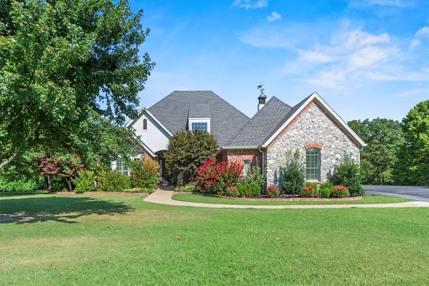Custom luxury estate on 10.22± acres in the Bentonville School District. This one-level, 3,917 sq. ft. residence plus 710 sq. ft. bonus apartment offers timeless craftsmanship, authentic hardwood flooring, cathedral ceilings with exposed beams, and three fireplaces. The renovated primary suite features vaulted ceilings, wood accents, bay window, oversized walk-in closet with custom built-ins, and a spa-like bath with heated floors and MicroSilk tub. Open living areas include a sunroom with UV-tinted windows, library, and gourmet kitchen with Bosch & Samsung appliances. Outdoor living shines with a gunite pool, waterfall, tanning shelf, and lush landscaping. Additional highlights: 3-car garage, smart home features, two Generac whole-house generators, sound system, and extensive storage. A new 2,000 sq. ft. steel shop includes a guest apartment with full kitchen and bath. Privacy, convenience, and resort-style amenities minutes from schools and bypass.
