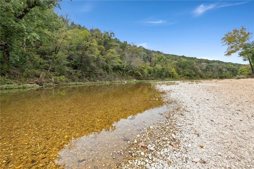Build your dream cabin retreat on the Kings River! This beautiful 3.28-acre lot is located in the established Riverside at Shady Grove community, known for its scenic setting and charming log and stone homes on spacious lots. Residents enjoy access to a private community gravel bar along the river—perfect for relaxing, building campfires, floating, fishing, and attending neighborhood events by the water. Ideally situated just 15 minutes from Eureka Springs and only 5 minutes from the Walmart in Berryville, this property offers the perfect blend of peaceful seclusion and convenient access to amenities, restaurants, and entertainment. Community building restrictions and covenants are available for review upon request. Detached buildings are permitted with approval from the Architectural Control Committee. Public water is available at the county road behind the lot. A whole-subdivision perc test is on file. The lot is ready and waiting for your custom cabin!