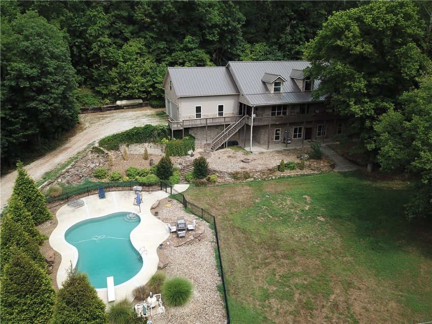 Welcome home to this incredible estate nestled on almost 30 acres of treelined countryside nearly in the heart of NW AR & just a short distance from Sugar Creek. This stunning home has 3 levels, 5 bedrooms, 5 baths, 2 separate laundry rooms (even a laundry chute) executive office w built-ins, 2 bonus rooms (one has separate outside access if needed), 3 car garage, & a hot tub to end your relaxing day. Home has new metal roof July 2022. Some features: an in-ground pool protected with iron fence, 50x50 enclosed metal shop building has heated & cooled office w half bath, meat cooler under 10' lean-to, & a 16' lean-to off side for added dry storage. Add'l features: hardwood & tile flooring on main & upper level, double ovens w propane cooktop (dedicated propane tank), & huge pantry. Lower level is sealed concrete, galvanized ceiling, wet bar, bedroom, full bath & laundry. Lower level grants direct access into the professionally landscaped yard & water fall feature, & stop by the separate pool garage to grab your toys.