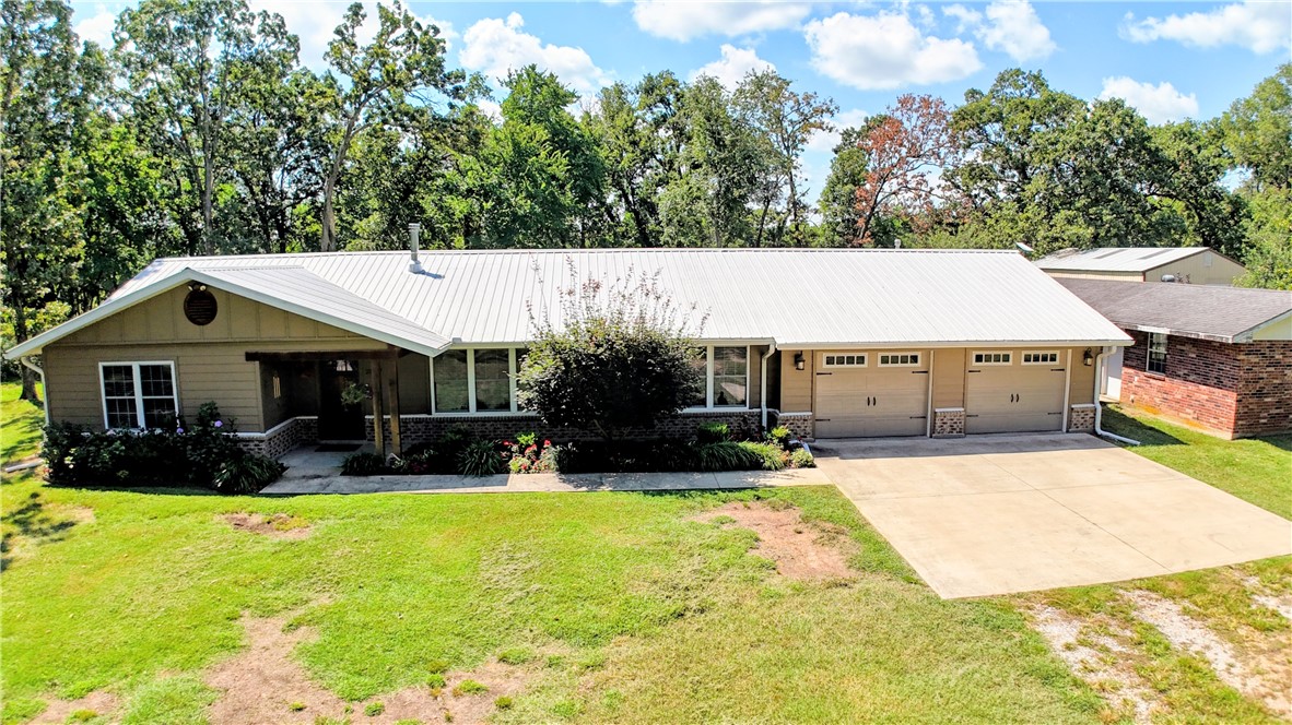 Great location-3BD, 2.5BA, 2,068 SF home on 5.13 acres! Open floor plan design, large bedrooms, 2x6 insulated walls, additional storage, including dual pantries & a wood-burning stove vented throughout. Hardwood in entryway & LR, carpet in bedrooms & tile in wet areas. Office offers a quiet retreat for reading/working from home. Eat-in kitchen w/ granite counters, breakfast bar, SS appliances & lots of cabinets. Oversized, 2-car garage, utility/mudroom w/ ample storage & lockers. Primary suite features tray ceiling, walk-in closet, soaker tub, separate dual vanities & walk-in shower. Outdoor features a pergola-covered patio, 30x50 shop w/insulated overhead door & electric, raised garden beds, chicken coop, fruit trees & grape/blackberry vines. Outbuilding has an irrigation pump. Rural water for house & well for yard. Whole-home 22kW Generac generator, upgraded electrical, 2021 HVAC w/ smart thermostat. Brick outbuilding offers guest/in-law suite potential, or make it a screened-in entertaining area! Survey avail.