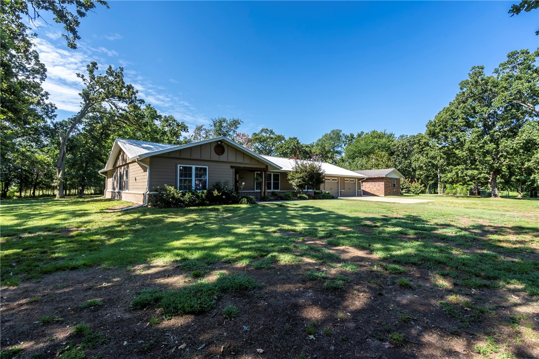 Great location-3BD, 2.5BA, 2,068 SF home on 5.13 acres! Open floor plan design, large bedrooms, 2x6 insulated walls, additional storage, including dual pantries & a wood-burning stove vented throughout. Hardwood in entryway & LR, carpet in bedrooms & tile in wet areas. Office offers a quiet retreat for reading/working from home. Eat-in kitchen w/ granite counters, breakfast bar, SS appliances & lots of cabinets. Oversized, 2-car garage, utility/mudroom w/ ample storage & lockers. Primary suite features tray ceiling, walk-in closet, soaker tub, separate dual vanities & walk-in shower. Outdoor features a pergola-covered patio, 30x50 shop w/insulated overhead door & electric, raised garden beds, chicken coop, fruit trees & grape/blackberry vines. Outbuilding has an irrigation pump. Rural water for house & well for yard. Whole-home 22kW Generac generator, upgraded electrical, 2021 HVAC w/ smart thermostat. Brick outbuilding offers guest/in-law suite potential, or make it a screened-in entertaining area! Survey avail.
