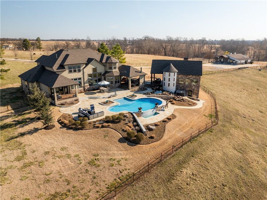 Stunning 40-acre one-of-a-kind equestrian estate with panoramic valley views. Open-concept home features 1BD/1.5BA on the main level w/dual living areas divided by a double-sided fireplace. Chef’s kitchen offers wood cabinetry, granite counters, walk-in pantry, integrated refrigerator, & butler’s pantry. Primary suite includes expansive stone fireplace, heated tile floors, Patina soaking tub, tiled shower & dressing room connected to utility. Office area offers built-in bookcases & views of fields. Upper level boasts living area, utility, & additional 3BD/2BA. 4-car garage with storage & in-ground storm shelter. Modern saloon with Lonesome Dove-inspired bar, loft above, workout room behind & heated patio outside. Below-grade, rock grotto has 1BD/1BA, gathering area & native stone wood fireplace. Outdoor amenities feature a heated gunite infinity-edge pool, koi pond, waterfall & covered outdoor kitchen w/ fireplace. Custom-built barn w/living quarters, stone FP, Priefert panel walker/stalls, storage & lighted arena.