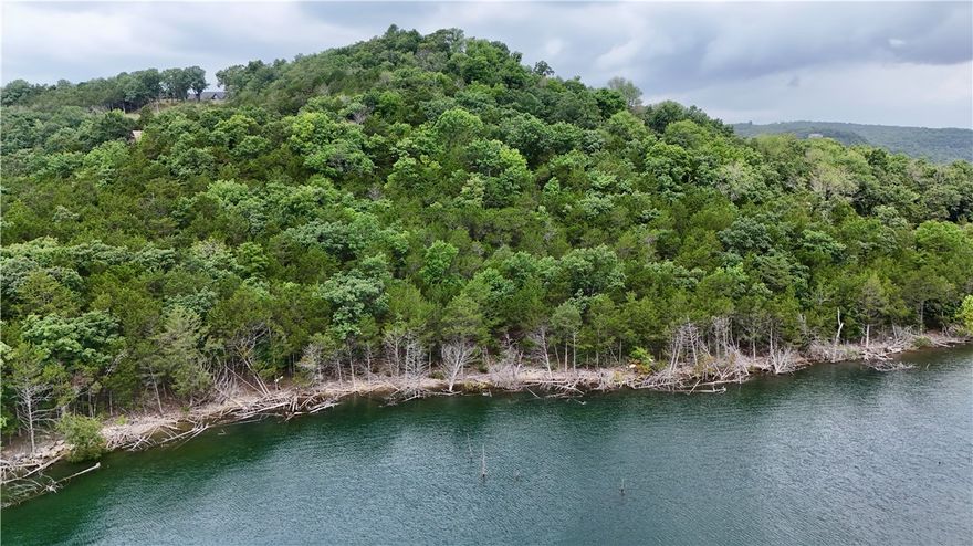 The Perfect slice of Beaver Lake Life Awaits YOU!!!  1.02acres 680ft of shoreline ZONED FOR BOAT DOCK on North end of Beaver Lake near Point 4 giving you Breathtaking Panoramic lake views.  Site is  Buildable with a level area nestled within a wooded buffer providing both flexibility and seclusion an ideal canvas for your dream lake home. Carefully selective clearing ensures unobstructed vistas across the water—perfect for sunrise and sunsets. Level building site is close to shore for easy walk to the water/shoreline!  Paved road access, available electricity, and ability to install well and septic systems with generous space remaining for outbuildings, motorhome parking, lake equipment and your own homegrown garden. 
Located in Cedar Acres subdivision close to Airstrip,  Lost Bridge Village, marina,  tennis, pool, and community hall.   
A clean canvas to design and build exactly how you envision whether it's a weekend getaway or a year-round residence.  Property zoned for private dock