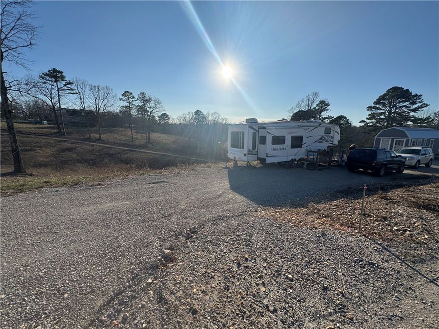 5.02 acres with leveled pad set up for camper living (camper does not convey). Includes 12x32 building with kitchen area, sink, and bathroom which will need finished .  Property features shared water, two septic systems, and two electric hookups. Ready for residential or recreational use.
