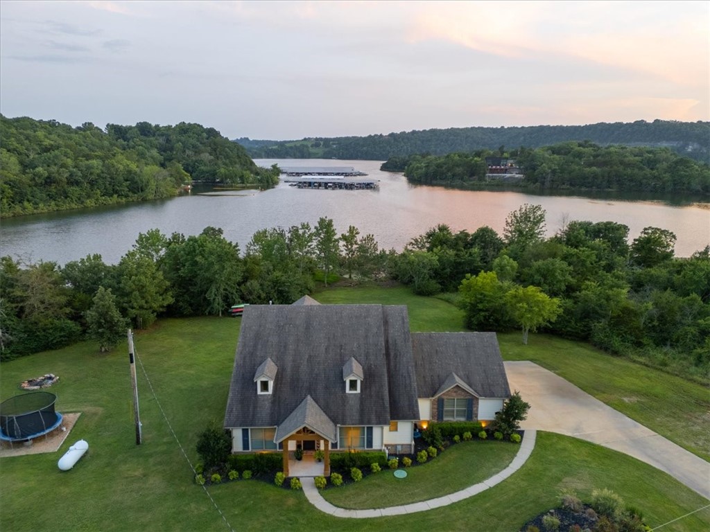 If you're looking for million dollar LAKE VIEWS and effortless LAKE FRONT access right off your back porch, this is the one. This custom-built 2017 lake home is a true unicorn, sitting on three flat acres with a spacious 24X24 shop. Step inside to find soaring vaulted ceilings, a stunning floor to ceiling stone fireplace, an oversized island with quartz countertops, and a large covered back deck overlooking the water. Just imagine the sunsets you'll get to enjoy. The primary suite is located on the main floor and features a spa-like walk in shower and a closet that conveniently connects to the laundry room. Two additional en suite guest bedrooms are also on the main level. Upstairs, you'll find a generous bonus space with a walk in closet, a full bathroom, and an abundance of attic storage. An above ground pool conveys with the home, perfect for summer days spent by the water. With views like these, every day will feel like a getaway while still having easy access to HWY 412 and just 5 minutes to War Eagle Marina.