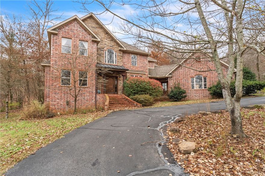 Discover peace and natural beauty at 2678 Creekstone Drive in Fayetteville, Arkansas.
Tucked away on a private road and surrounded by five serene acres, this stunning brick home blends seclusion, comfort, and gorgeous scenery.

Inside, white oak floors, spacious living areas, and an amazing floor-to-ceiling stone fireplace anchor the warm, inviting interior. Large windows frame beautiful views of the property, filling the home with natural light and a constant connection to the outdoors.

The remodeled master suite offers a luxurious, retreat-like atmosphere with thoughtfully updated finishes and a calming sense of privacy.

Behind the home, a seasonal waterfall adds tranquil sound and charm to the landscape. Whether enjoying a quiet morning on the porch or hosting friends, this peaceful setting offers unmatched privacy and relaxation.

With its picturesque surroundings, timeless craftsmanship, and serene atmosphere, this home is a rare private retreat just minutes from everything Fayetteville offers.