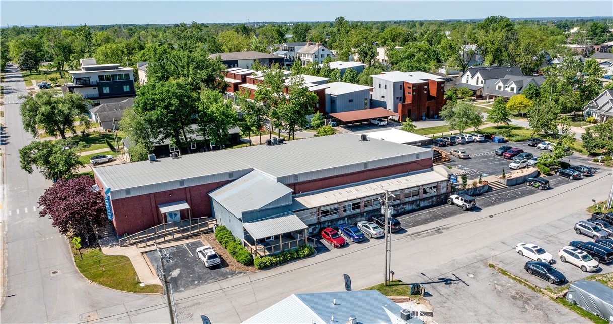 This property is conveniently located within walking distance of the new Walmart corporate campus and downtown Bentonville. It sits adjacent to The Momentary and the 8th Street Market, placing it in a vibrant and culturally rich area. The building features a 1,200-square-foot commercial kitchen equipped with two hoods and a grease trap, making it ideal for food and beverage operations. On the east side, there is a potential space for a food and beverage venue, highlighted by a glass garage door that opens toward The Momentary. Additionally, the property borders a major trail intersection on its south side, integrating seamlessly with the area's extensive trail system. It is also situated in the 5th Street Entertainment District, a lively corridor located between the Bentonville Square and the Walmart Headquarters.