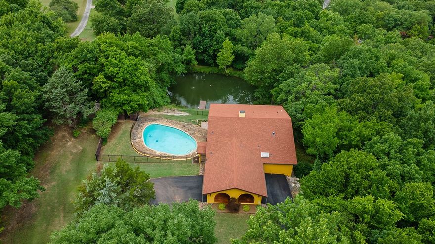 This Mediterranean, Mid-Century Modern home is an absolute one-of-a-kind show stopper. Located on 2.13 secluded acres at the base of Kessler Mountain, this urban setting feels like a Spanish country villa. Inside, you’ll find a remodeled kitchen with Cotto tiled floor, leathered granite, Talavera tile backsplash, Chef’s grade Verona gas range and eating area.The living room boasts a vaulted ceiling with porcelain tile wood floor, ornate wooden beams & built-ins.The massive 4-sided native stone fireplace is framed with custom wood Masonite wall paneling.Enjoy the 500 sqft screened-in terrace w/ arches as a prime entertainment space.The exterior is authentic stucco with an inviting portico and arched Pella glass doors & windows w/ custom wood shutters. A native stone decked saltwater pool overlooks the mature trees and large Artesian well fed pond. Spanish iron hand blown amber glass light fixtures.Basement workshop. New asphalt drive.Under sink water filter. Minutes to I49 & UofA. Fayetteville Schools.