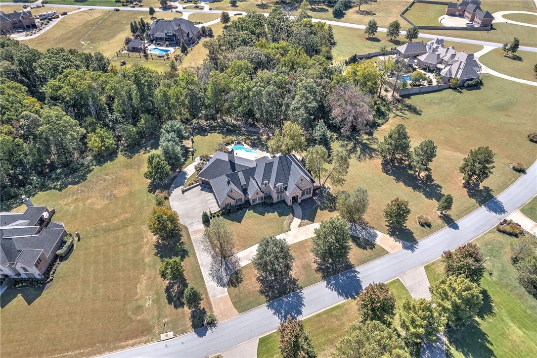 Nestled on a serene 2.02 acre lot in desirable Talamore Subdivision. This stunning home features hand-scraped hardwood floors, wood-cased windows, and substantial crown molding throughout, showcasing all the attention to detail. This sprawling 6218 sq ft home has 5 bedrooms, 4 full baths, 3 half baths, with an open floor plan that has the perfect great room for gatherings! The chefs kitchen is a culinary paradise with high-end appliances, custom cabinets with pull outs, pot filler, and a 10X5 island with storage on 3 sides. Family room features vaulted ceiling, wood beams, and a floor to ceiling rock fireplace. Whether you are in the Billiard room, watching a movie in the theater, or enjoying the pool and tranquil outdoors, you have endless entertainment options. Oversized heated 5 car garage. Storage galore, too many features to mention. See attached amenities list. Home is 5 miles to the Bentonville Square and all it has to offer in the Art and Entertainment District with an abundance of amazing restaurants.