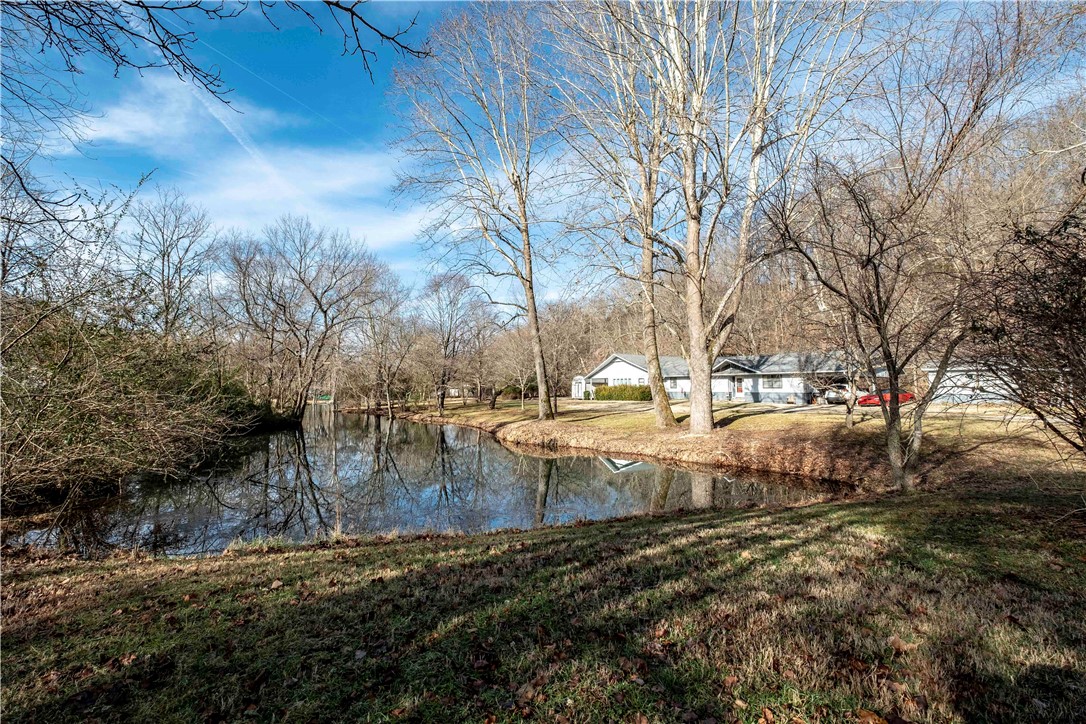 One of a kind location! Live Creek! Imagine opening your windows at night and hear the creek lulling you to sleep...or you might prefer the view of the lagoon/pond. Beautiful one-level home backs up to brush creek on 3.63 acres m/l of land! Highway access is close by. This 3 bedroom 2 bath home has loads of windows with an amazing view of the creek. the home boasts a 16x32 7ft deep in-ground pool and a shared lagoon out front. home has a wood stove, large sunroom, and deck. Attic fan,2 inch blinds in most rooms, hardwood floors part of house, cathedral ceiling living room,walk in closest. Will require flood insurance.sunporch, deck off the back, porch board ceiling one room, built-in buffet. Storage building, woodstove in sunroom does NOT convey.