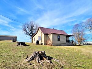 Cozy country charm with an incredible view in this 3 bedroom, 1 bath that dates all the way back to 1905. Updated with a new metal roof, new windows, central heat & air, new Martha Stewart kitchen cabinets, new fixtures and appliances, and updated wiring and plumbing. This home includes beautiful hardwood flooring and while the home is on rural water, there is an original cistern inside which has been closed up adding to the country vibe and serves as a conversation piece table! Located just outside of town sitting on a little over half an acre. A newer 24'x12' storage building is outback which includes a full garage door and ramp. Property also includes a cellar with electric available.