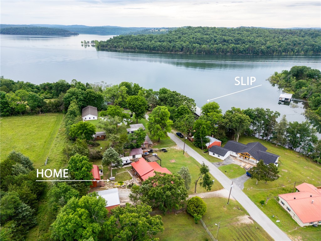 Don't miss this cabin style lake property offering unparalleled beachfront-like access & versatility featuring a boat slip with a 6500# tri-toon lift. Situated on 0.38 acres at LaRue on Beaver Lake, the 2-bedroom, 2-living area main house is designed for both comfort & entertainment. Enjoy year-round lake views from the remodeled covered deck, pergola, & outdoor firepit area. The guest house built in 2022 provides additional living space with a bedroom, half bath, walk-in closet & two lofts. The property also features extensive updates, including fresh interior paint, remodeled bathroom, brand new carpet, LVP flooring, custom cabinetry + pantry, WeatherBarr windows + sliding door, a tankless water heater, & a 2020 HVAC system. Not only that, but the 24x30 shop, extensive landscaping, raised garden beds and of course the convenient lake access make this a perfect getaway.