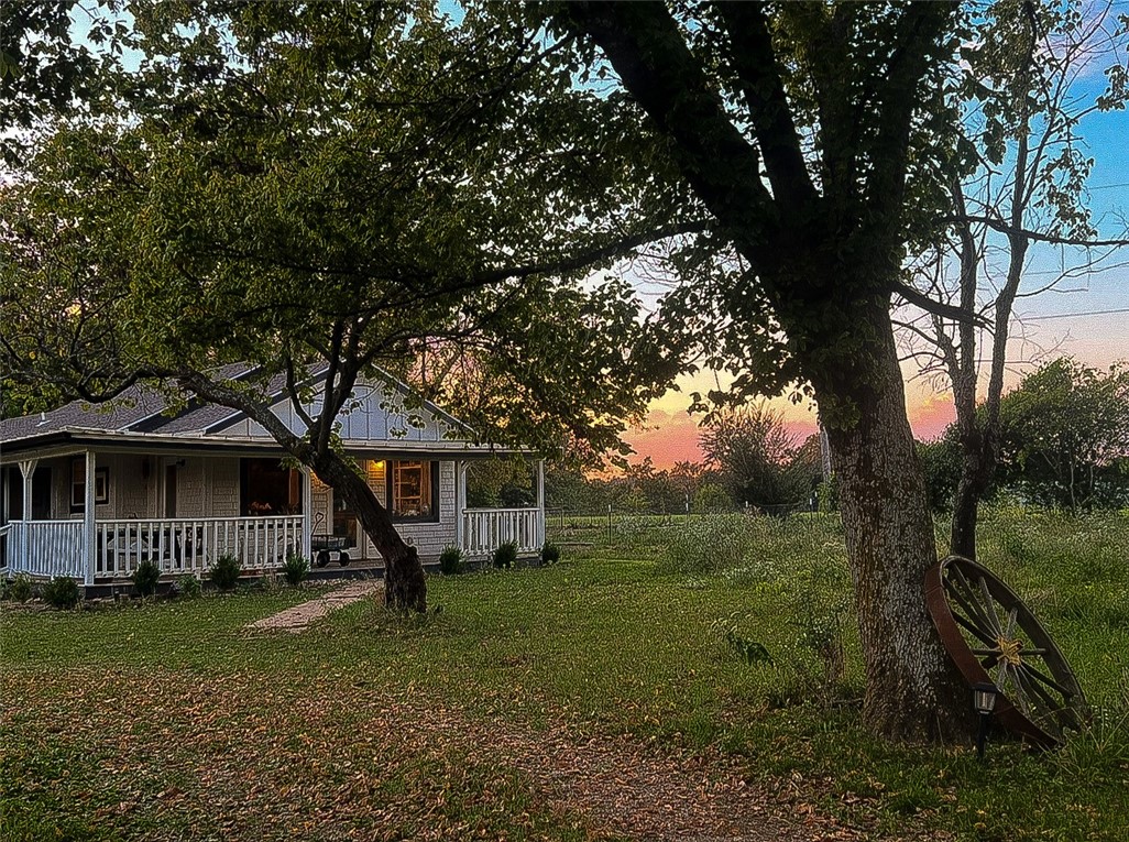 Garden and horse folks, look no further. This renovated cottage-style farmhouse on 4.11 acres (two lots) is an open plan with all the comforts, including an upgraded tankless water heater and clawfoot tub in the master bath. This tucked-away home has beautiful views and good neighbors. New vinyl plank floors by Stainmaster are guaranteed pet and waterproof. Bedrooms and living room have modern ceiling fans. With electric appliances, including HVAC, and a new roof. Wood stove riser has a chimney, but needs hookup. Enjoy a gentle breeze on the wraparound porch overlooking two gardens, apple trees and passion fruit. Established grapevines grow up the carport beside black raspberry and roses with native flowers. A shed with fenced yard is ready for poultry or goats, and the large barn is a blank canvas. Property is fenced, with gates on both ends and at the driveway. Just 2.5 miles from town and 35 mins to Fayetteville. Come home and set up roots.