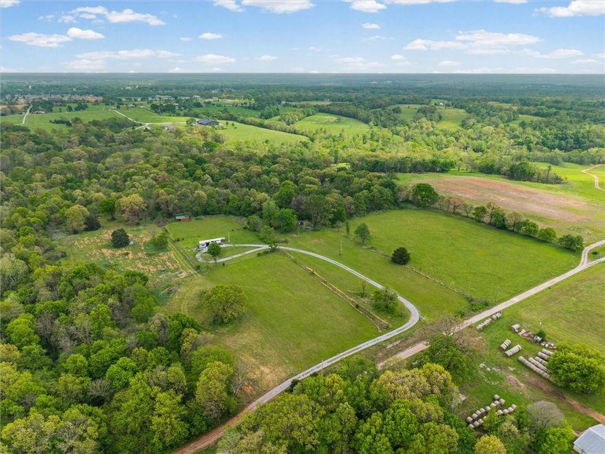 Experience true peace and quiet on this beautiful 10-acre property tucked away at the end of a quiet dead-end road just minutes from Gravette. This setting offers a level of privacy and calm that is increasingly hard to find. The front 5 acres are cleared and build-ready, featuring stunning west-facing sunset views, while the back 5 acres offer mature woods and a wet weather creek, creating a natural buffer and added seclusion. The wooded area also provides excellent habitat for wildlife, making it well suited for recreational use or hunting. Electric, water, and septic are already on site, plus a second electric and water connection is available. A small hay shed provides functional storage. Accessed via a gravel driveway easement, with some existing wire fencing. Enjoy relaxed rural living just minutes from Gravette and within easy reach of Bentonville and Rogers. Also available as two 5-acre tracts MLS 1343303 & MLS 1343307