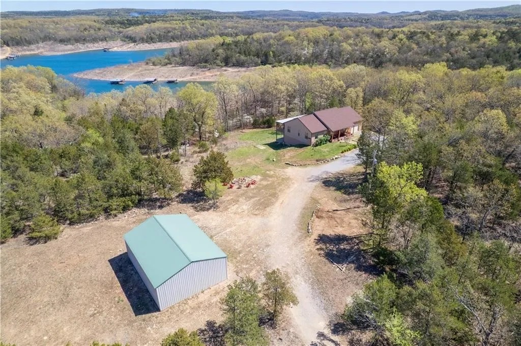 Exceptional Bull Shoals Lakefront Estate | 23 +/- Acres | Private Dock | Custom Home | Shop. Welcome to a lakefront estate on the shores of Bull Shoals Lake in Marion County, Arkansas. This home features craftsmanship, and modern comfort—perfect for those seeking a peaceful residence or a recreational getaway in the Ozarks. Built with enduring quality and completed with care by the family of the original builders, the home showcases attention to detail throughout. Features western cedar siding and metal roof. The main level offers 1,800 +/- sq ft of living space featuring, cherry flooring and cabinetry, cedar-lined closets, and a covered back deck stretching over 50 feet—perfect for enjoying the seasonal lake views. The finished walk-out basement provides another 1,800 +/- sq ft of living space, with a second kitchen, full bath, large living area, bonus room, and multiple utility/storage rooms. Includes a boat dock with two slips. A shop offers ample room for hobbies and tools.