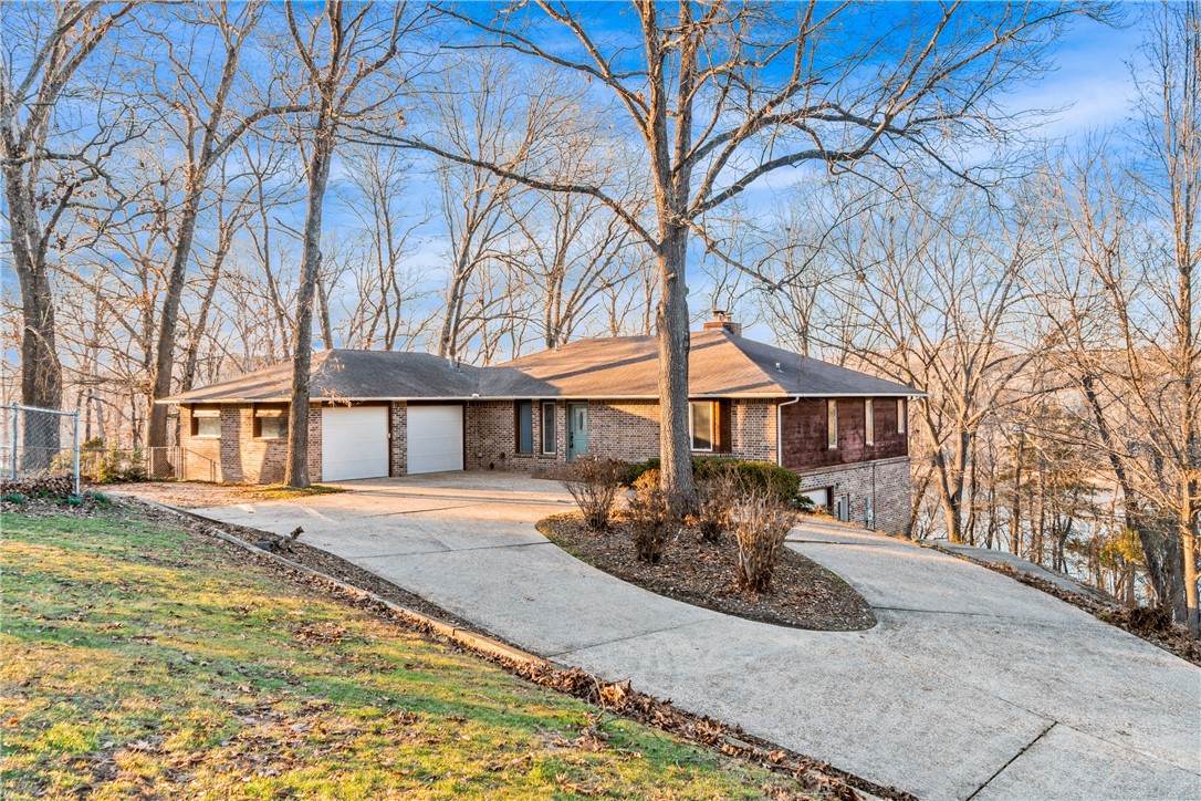 This beautiful 4-bedroom, 3-bath Lakefront home offers a prime spot on Beaver Lake, complete with a boat slip and a jet-ski slip, and is conveniently located less than 10 minutes from downtown Rogers. Enjoy an open floor plan with abundant natural light throughout, plus a finished walk-out basement featuring two bedrooms, a living area, and a workshop. The kitchen and dining area both overlook the lake, making every meal feel like a getaway. The primary bedroom boasts a sitting area with a stunning lake view, a walk-in closet, and an exceptional view of the lake. Access the dock with ease, only a short walk away. This lake home is a dream!
