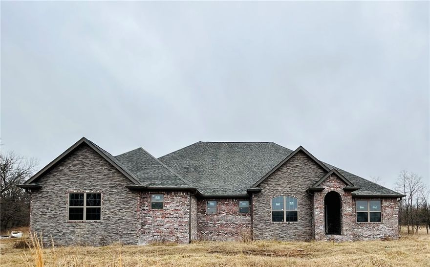 Incomplete new construction waiting for your final touches to make your dream home. BY APPOINTMENT ONLY! Beautiful Brick and Stone, 3400 sq foot heated and cooled, 4 bedroom 3 1/2 bath with 4 car garage (insulated doors)  9.75 acres on Spavinaw Creek. This home has 1000 gal buried propane tank, septic tank installed, 400 Amp service will provide plenty of power to add a shop, HVAC electric with propane backup, 10yr parts and labor warranty installed,complete with ductwork sprayed with foam insulation, exterior walls and ceiling are foam insulated, interior walls insulated with batts for noise control. Exterior includes gutters. Great open concept with a large walkin pantry. Master closet is a concrete lined storm shelter.  All bedrooms wired for wall mount TV. Plumbed for central vac, wired for aprox 63 can lights, additional breaker box in laundry to add on. Plumbing and electric is all roughed in, sheetrock textured and primer. Great private location, beautiful view,8 mi to I49.Generator and Central Vac installed