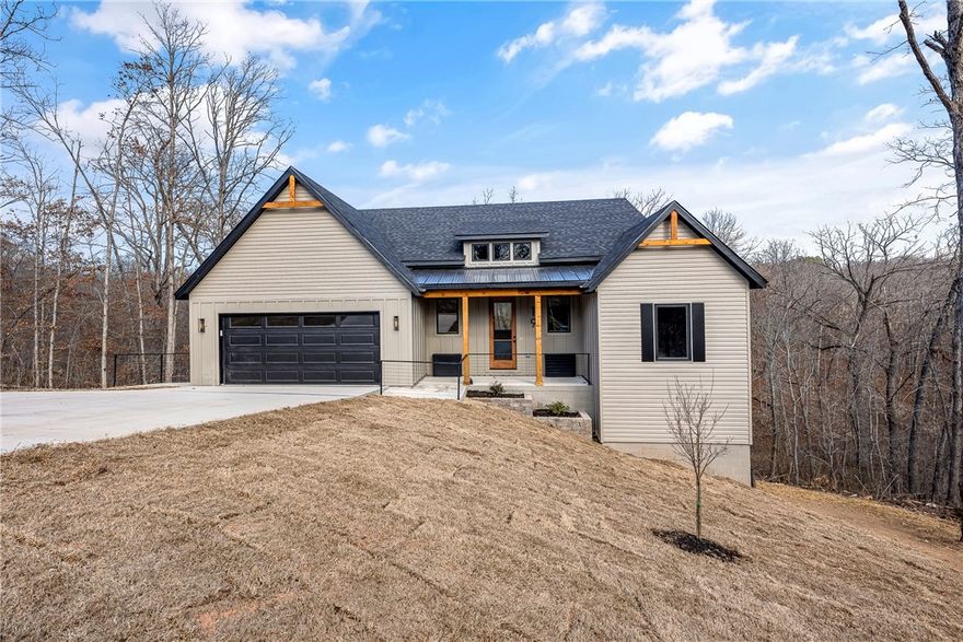 Welcome to 19 Carsphairn Lane — a beautifully designed transitional-style home tucked away on a quiet cul-de-sac offering privacy and a peaceful setting. Step outside to the two-tier deck, perfect for entertaining or relaxing while overlooking the wooded POA surroundings. Conveniently located near Bella Vista’s trails, lakes, golf courses, and everyday amenities, this home blends timeless design with modern Northwest Arkansas living. Inside, enjoy a warm and inviting atmosphere highlighted by moody granite surfaces, thoughtfully designed lighting, a propane range, and a hidden pantry that adds both function and clean design appeal. High ceilings, huge windows, spacious bedrooms, and a private office create a bright yet cozy space ideal for everyday living and entertaining. Includes a 1-year builder’s warranty for added peace of mind.