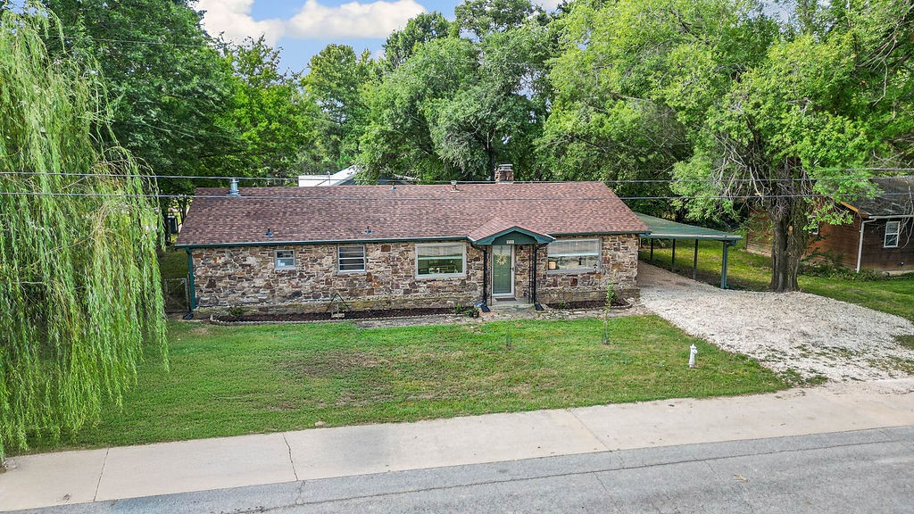 Charming rock home on a quiet corner lot minutes to downtown, the aquatic park, and Hwy 62. Light-filled living room with custom rock fireplace opens to a sitting area and the kitchen/dining with white cabinetry, modern hardware, ample counters, and a gas range. Oversized primary bedroom with half bath and walk-in closet; two additional bedrooms and a full bath with double vanity. Enjoy a large screened back porch overlooking mature trees. Insulated flex/utility room off the porch adds storage or potential office/guest space, plus an insulated 8Ć12 shed. Recent updates include roof, gutters, gravel drive, windows & blinds, attic insulation, storm door, HVAC (AC & furnace), security/internet systems, landscaping, and fixtures. Appliances convey; select furniture may remain.
