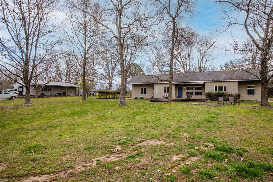 Idyllic Green Acres with 34 acres, 2100sf home and 30x60 shop are increasingly difficult to find. Set off the road about 600', a grove of trees provides seclusion and tranquility with Rogers, AR an easy 15 min drive away.  Only 1.5 from Garfield's famous Shortstop Ice Cream Cones and 4 miles from Lost Bridge Marina, the entry crosses a small, continuously running creek that has open land entrances on each side to buildable areas with 5+acres each.  Continuing up the drive, the land opens up to the home and shop with ample room on all sides for additional outbuildings, homes or acres of land for recreation.  
If smaller acreage is desired, the land could be easily separated into parcels and sold for home sites.  
For those looking for something close to town but a remote, hidden gem, Green Acres is the place to be.