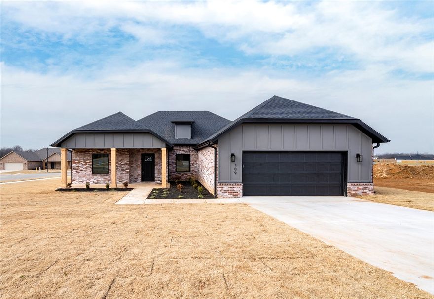 Striking new construction with curb appeal featuring a modern brick and siding exterior, covered front porch, and clean architectural lines. Inside, tall ceilings and expansive windows create a bright, airy atmosphere throughout the open living space. Wood-look tile flooring flows seamlessly into a beautifully finished kitchen with white cabinetry, dark countertops, stainless appliances, gas range, and an oversized island accented by stylish pendant lighting. The living room is anchored by a sleek fireplace with custom shelves, adding both warmth and character. The primary suite offers a peaceful retreat and a spa-inspired bath showcasing a fully tiled walk-in shower, black-framed glass, and contemporary finishes. Secondary bedrooms provide flexibility for guests, office, or any other needs. Energy-efficient construction, modern lighting, ceiling fans, and thoughtful design details throughout. Conveniently located in a growing neighborhood with easy access to parks, schools, and everyday amenities.