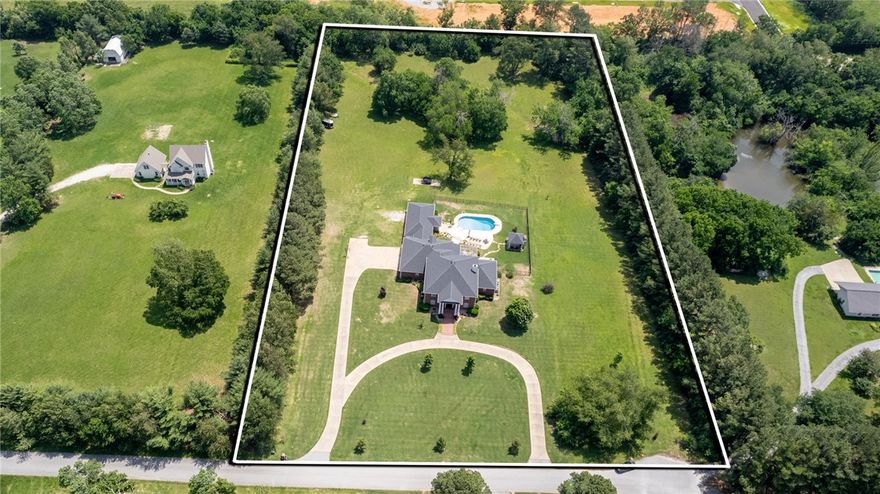 Rare Estate Property on 4.98 acres in Rogers, featuring an immaculate custom built colonial home, full inlaw suite & heated, saltwater pool. Sought after location in the Uptown Rogers shopping, dining, entertainment district! All new interior paint and flooring.This 5,932 SF home offers multiple living spaces & 4 bedrooms with private baths. Home office, formal dining room, renovated kitchen w/abundant cabinetry, an island, pantry & eat in area with fireplace. Formal living room includes raised ceilings,fireplace, large windows & patio access, while a living room on main level adds extra gathering space. Primary suite boasts a fireplace, sitting area & luxurious attached bath. Upstairs are two guest bedrooms with baths and walk-in closets and 2 bonus rooms ideal for media & game spaces. A breezeway leads to the guest suite with full kitchen and bath. Outdoors, enjoy the patio, pool and gazebo with fireplace, surrounded by lush landscaping. Updates include a new roof ‘20, HVAC & water heater ’18 & pool liner ‘23.