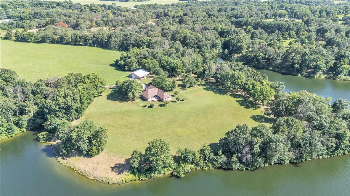 Escape to your 3.16 acres of flat, pristine lakefront paradise on the lake, with approx. 0.7 miles of shoreline and panoramic views. Nestled on a private drive, far from neighbors, this immaculately maintained 2,293 sqft, 3-bed, 2-bath home, built in 1992, offers a split floorplan. Additional features include a 2022 roof, granite countertops, high-end wood-burning stove, advanced water filtration system, custom shelving in the pantry and primary closet, and a serene sunroom with stunning lake views. The east-facing lot boasts nightly sunsets over the lake w/ a huge 50x30 insulated shop that electric, water, and plumbed for a bathroom. An idyllic fenced orchard/garden completes this secluded gem. Ideal for tranquil living, this private point-lot retreat is a rare find. Schedule your tour now!
