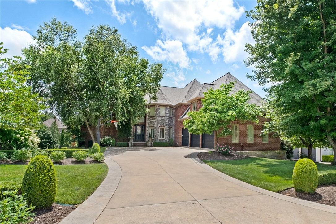 Located in a gated luxury neighborhood, this stately three-level home is a masterpiece of brick and stone. Inside, the grand living room features a two-story ceiling, a beautiful fireplace with a dark wood surround, and a balcony overlooking the space. The gourmet kitchen is a chef's dream with white cabinetry, a large center island with seating, a professional-grade range, and elegant gold light fixtures. This home offers 6 bedrooms, 6 bathrooms, and 2 half bathrooms, with all bedrooms featuring en suite baths. The primary bedroom is a serene retreat with a spa-like bathroom boasting a soaking tub, a large walk-in shower, double vanities, and marble. For entertainment, the home offers multiple game rooms and a dedicated media room. The backyard is an entertainer's paradise with a luxurious swimming pool, a large patio, and a covered outdoor living area with a stone fireplace and a built-in bar. The home is conveniently located close to shopping, I-49, the Walmart AMP, and local trails.