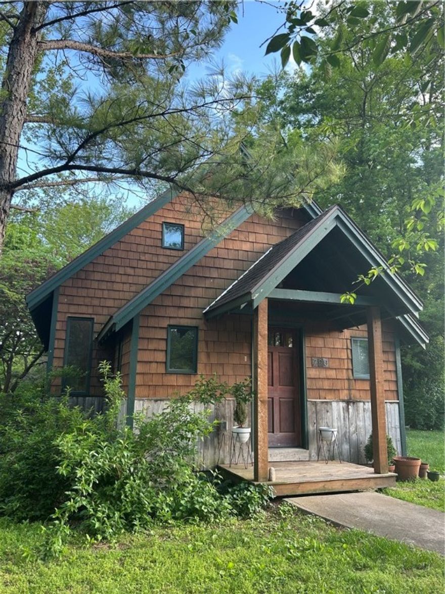 This cottage-style home by renowned architect Ross Chapin using his Three Gable Home plan is a blend of Craftsman detail and cozy elegance. This two-bedroom, one-and-a-half-bath design showcases Chapin’s signature style. The exterior features a steep-pitched roof with three distinct front-facing gables, wide overhangs, and exposed rafter tails. Cedar wood siding and covered front porch invite you in with warmth and character. Inside, the floor plan maximizes comfort and functionality. The open-concept living, dining, and kitchen area is anchored by rich wood trim, built-in cabinetry, and large windows that bathe the space in light. Vaulted ceilings and clever storage make the home feel larger than its square footage. The primary bathroom is designed with Craftsman detailing while the half-bath adds convenience. The home highlights a spacious patio and large fenced backyard extending the living area. A new 14x20 shed can be used as a small shop or extra storage space.