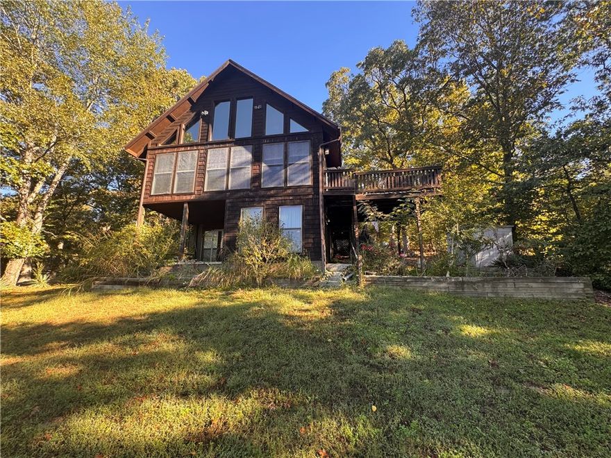 Lake Avalon Waterfront Retreat! This 3-level, 2,016 sq. ft. waterfront cabin offers direct lake access with a gentle paved path to the dock - no steep climb needed. The home features cathedral ceilings, massive lake-view windows, and an open main-level living area perfect for entertaining. The main-level master suite includes a walk-in closet and ensuite bath, while the loft bedroom with half bath and walk-out basement with family room and sunroom add plenty of space for guests. Multiple decks and patios maximize lake views and outdoor living. Located just 0.5 miles from the Play Thru Trail (connecting to the Tunnel Vision trail system) and 1 mile from Tanyard Creek Nature Trail, this home is perfectly positioned for vacation rental income. Add a few kayaks at the dock and this becomes a high-demand short-term rental that practically markets itself. This is a great opportunity to own income-producing lakefront property in Bella Vista! Sold As-Is. Professional photos are coming soon.