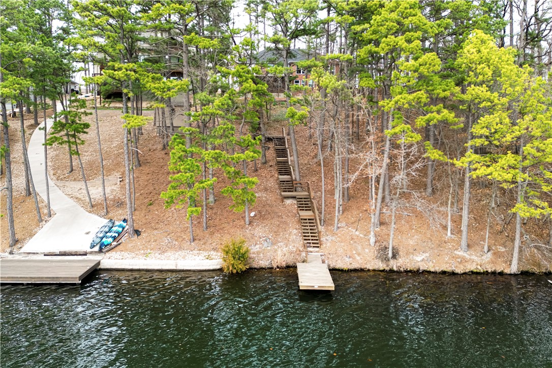 Lakefront all brick!Pine trees.Extra lot available see below!Skyrocketing ceilings,walls of glass,absolutely stunning lakeviews..44 acres.One Owner Custom Built! New roof 2023,new heating &air 2021.Gorgeous landscaping.Beautiful woodwork & built-ins,many different ceiling heights,granite & solid surface countertops,solid wood cabinets,china hutch,breakfast bar,2 dining areas,2 bedrooms,2 baths,utility room huge+fold down ironing board.Downstairs could be another home perfect for an air B&B,in-law apartment.Bluebird & Mountain biking capital United States self proclaimed! Bike trailhead closeby when completed.Downstairs totally other home!Large living room,main bedroom,2nd bedroom,large bath!Outside has solid maintained stairs to dock.Lots of Deck area & outdoor living!Enjoy the lake!Fishing?Kayaking?Canoe?Pontoon,2 car garage.Lots of storage!Close to shopping,trails,Country clubs,golf courses,swimming pools.outdoor/indoor.Exercise areas!Extra lot.51 acres can be purchased separately$115,000 ask your agent 4 details