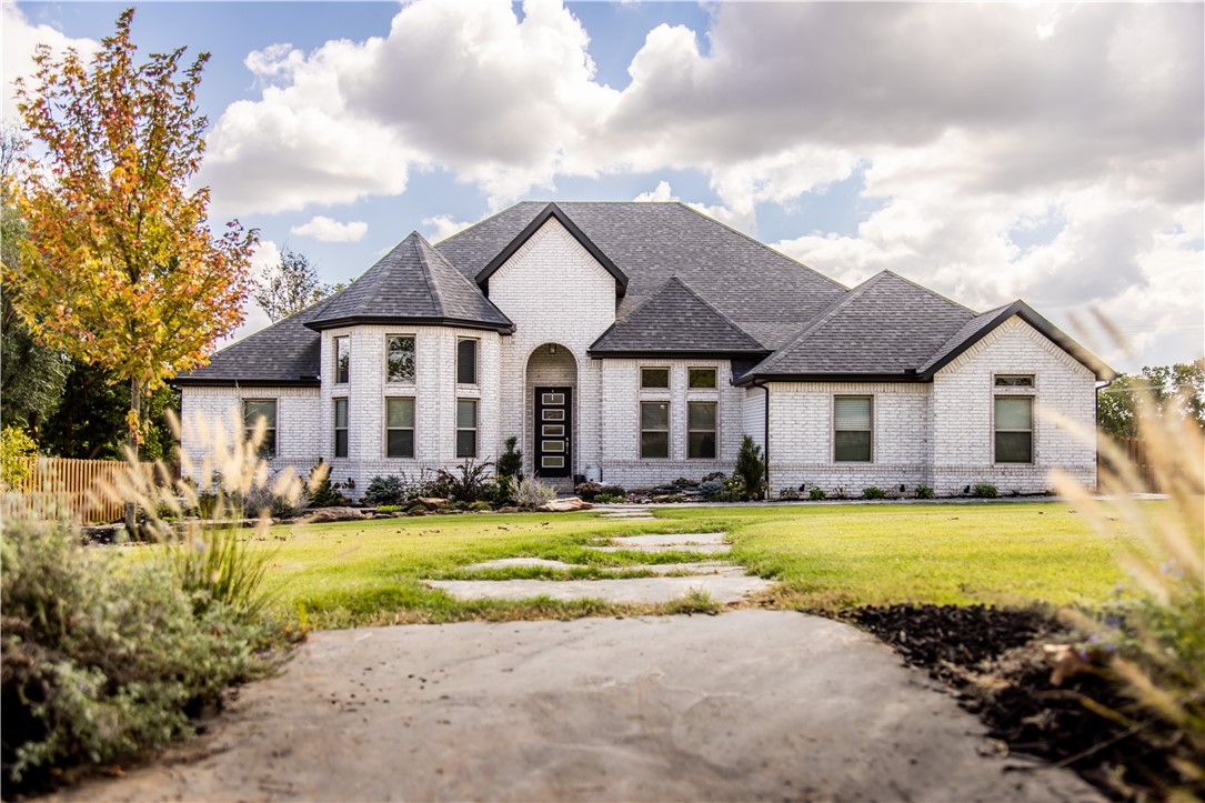 This gorgeous home, set on a 0.68-acre lot, offers a perfect blend of modern design and comfortable living all on one level. The spacious 4-bedroom, 3-bathroom split floor plan ensures privacy, with the large primary suite tucked away for relaxation. The open living room features cathedral ceilings with wood beams and a cozy fireplace, flowing seamlessly into the kitchen, which boasts a large island, pantry, and breakfast nook. Entertain in style with a formal dining room and a generous study with 14' ceilings. Each of the three guest rooms are conveniently located adjacent to a full bathroom, offering comfort for visitors. This home offers a laundry room with a clothes drying rack, sink, and built-in storage, plus it is perfectly situated between the primary closet, 3-car garage, and kitchen for easy access. Step outside and enjoy the covered back patio with tiered deck, overlooking a beautifully landscaped yard plus built-in hammock stands, cozy fire pit, and hot tub, ideal for gatherings and outdoor enjoyment.