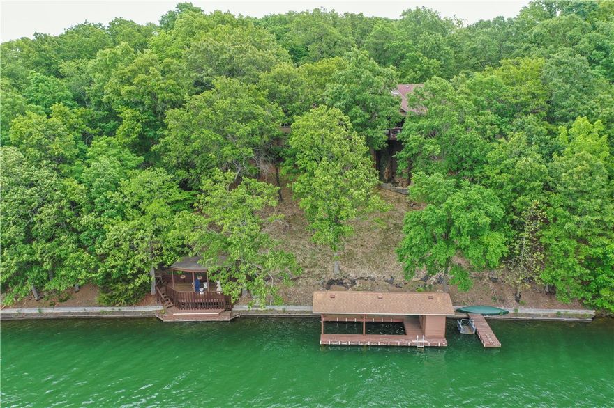 Walkdown to lake and private boat dock! This stunning 5,060sf home is nestled on 1.44 acres of cleared woodland and has over 380' of Lake Loch Lomond shoreline. You will enjoy the panoramic views from every room of pure Ozark majesty while enjoying Bella Vistas largest lake and the only one with a fuel refill and marina.  But, lets get to the real gem, this house! The main floor is open and expansive with beautiful wood floors throughout. From the time you walk through the gorgeous front french doors you will see the luxurious touch put into each detail. Large kitchen with massive island for the gourmet chef, surround windows to the flora and fauna of nature for the bird watcher, or take a gentle stroll down to your dock and drop a line in. The main floor has so much to offer from the sweet parlor to the large owners suite with ensuite bath and a closet for a true clothes lover. The downstairs is a complete guest suite with rumpus room and kitchen! Too many amenities to mention so book an apt today!