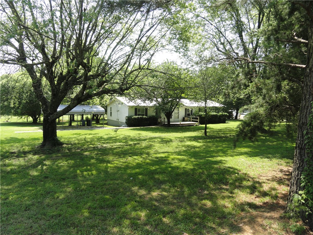 Escape to the country in this spacious and open double-wide. Sitting on almost 1 acre, this home is anchored, has a metal roof (6 years old), gutters, central heat & air, plantation shutters, a garden tub, skylights, double pane windows, two decks, a detached carport, two sheds (one with electricity), a storm shelter and so much more!