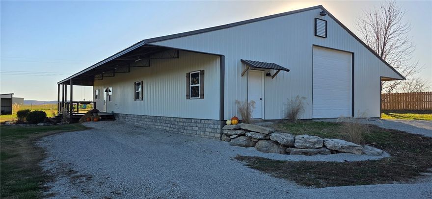 Stunning Barndominium on 5+ Acres in The Meadows. Experience Ozark living in this beautifully designed, low-maintenance barndominium on 5+ peaceful acres in the desirable Meadows Subdivision, just minutes from downtown Berryville. The home features metal siding and roof, radiant-heated stained concrete floors, and an open-concept layout. An outside wood furnace efficiently supplies heat to the water heater and radiant flooring. The gourmet kitchen offers cherry cabinetry, stainless steel appliances, and ample counter space. The main-level primary suite includes an ensuite bath and walk-in closet, along with a convenient half bath and oversized laundry/mudroom. Upstairs are two large bedrooms and a dedicated children’s library/playroom. The fully fenced property is ready for livestock and includes a 40x40 insulated shop/garage with foam insulation, automatic overhead door, and workbenches. Rural water, septic, home warranty, and a brand-new HVAC system scheduled for January 2026 complete this exceptional property.