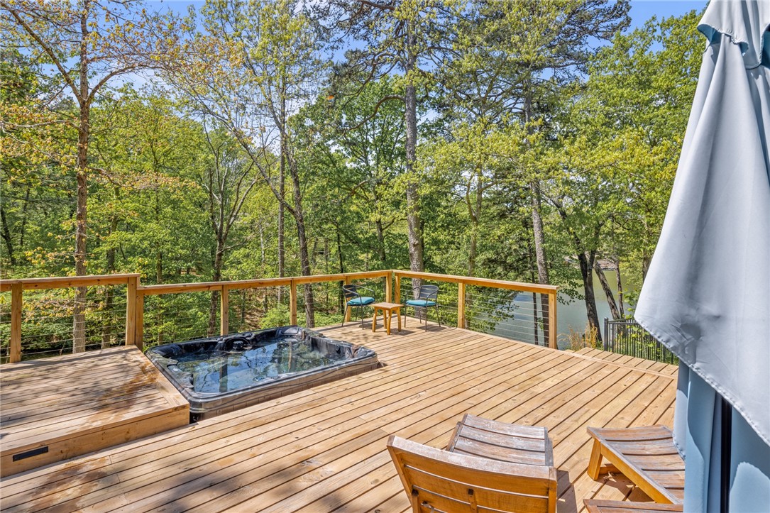 Lake front home with panoramic views! Renovated interior w/2 living spaces, sunroom, extra storage & more! Custom-built outdoor oasis w/lake views from covered patio & deck featuring a built-in hot tub, outdoor kitchen & access to dock. Main living space features large windows, natural light, stone fireplace & wood beam ceiling add beautiful design features. Sunroom is a relaxing space to immerse yourself in the outdoors. Kitchen has new sink, hardware and large pantry! Primary suite on main level has attached bath. Guest bedroom & bath. Fully finished basement featuring huge media space w/custom accent wall, wet bar and access to covered patio w/FLAT yard space! 3rd bedroom could be another primary suite w/access to full bath. Add storage/office space. New paint, flooring & light fixtures throughout. Backyard space features lighting, new stairs/railing to dock & rare fenced, flat yard space for this half acre lakefront lot. Enjoy the fantastic amenities incl. pools, gyms, lakes, golf courses, biking trails & more!