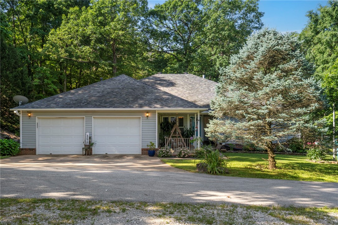 Welcome to your private retreat on 7 acres in Prairie Grove. This 4 bed, 2 bath home features hardwood floors, a spacious living area with a gas fireplace and blower, a dedicated office, and a sunroom with heating and cooling. The kitchen offers double ovens and a smart thermostat, with plenty of storage throughout. Enjoy the peace and wildlife from the front porch or soak in the hot tub out back. Recent updates include a new roof and gutters on both the home and 30x40 wired shop (Nov 2024). Additional features: 2-car garage, 40' RV cover, chicken coop, raised garden, paved drive, and dual access roads. Utilities include Washington Water, Ozark Electric, and Ozark Go internet. Quiet country living with quick access to town—don’t miss it!