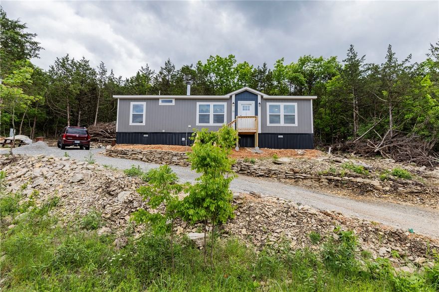 Built in 2025, this like-new manufactured home on a permanent foundation sits on a quiet cul-de-sac in Holiday Island on the high side of the street with scenic views. Bright windows filled the home with natural light and showcase frequent wildlife sightings including deer, birds, and squirrels. Enjoy a peaceful setting just minutes from golf, the marina, Table Rock Lake and amenities.