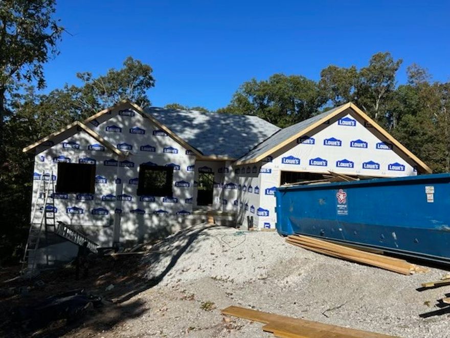 Secure this beautiful new construction by Elite Thomas Homes early to lock in current pricing and personalize select finishes and upgrades. Construction is underway with framing complete and an estimated completion date of mid-January 2026. Ideally located on the east side of Bella Vista near Lake Windsor, the property backs to the Tunnel Vision bike trail, offering direct access to the trail system just off Hampton. Inside, you’ll find an open-concept layout with vaulted ceilings accented by beams, a stack-stone vent-free gas fireplace, and wood flooring throughout the main living areas, hallways, and the primary bedroom (including the closet). The split floor plan offers privacy, with bedrooms 2 and 3 finished in carpet. The primary suite features a spacious bath with dual vanities, a large tiled shower with two shower heads, and a linen closet. Enjoy outdoor living on the covered deck just off the kitchen, perfect for morning coffee. Contact me for a full list of finishes and available upgrades.