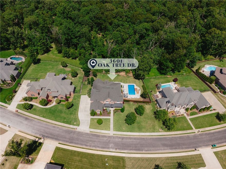 Set on 1.98 acres in Oak Tree Estates, this stunning home offers luxury living with resort-style amenities and an ideal layout. Featuring 5 bedrooms with direct bath access, a home office, bonus room, media room with wet bar, and spacious open living areas filled with natural light and wooded views. The chef’s kitchen includes a large island, KitchenAid appliances, built-in refrigerator, 6-burner gas cooktop, espresso machine, and oversized pantry. The primary suite is a true retreat with vaulted beamed ceilings, fireplace, spa-like bath, and custom walk-in closet connected to the laundry room. 2nd Level features 2 guest beds w/en suites & another 2 beds sharing jack & jill bath. Bonus room with half bath and attached media room w/wet bar. Outdoors, enjoy a spectacular pool with slide, hot tub covered patio with fireplace and built-in grill, multiple entertaining spaces, iron fencing, and expansive yard space. Located in a sought-after community with easy access to Downtown Bentonville and I-49.
