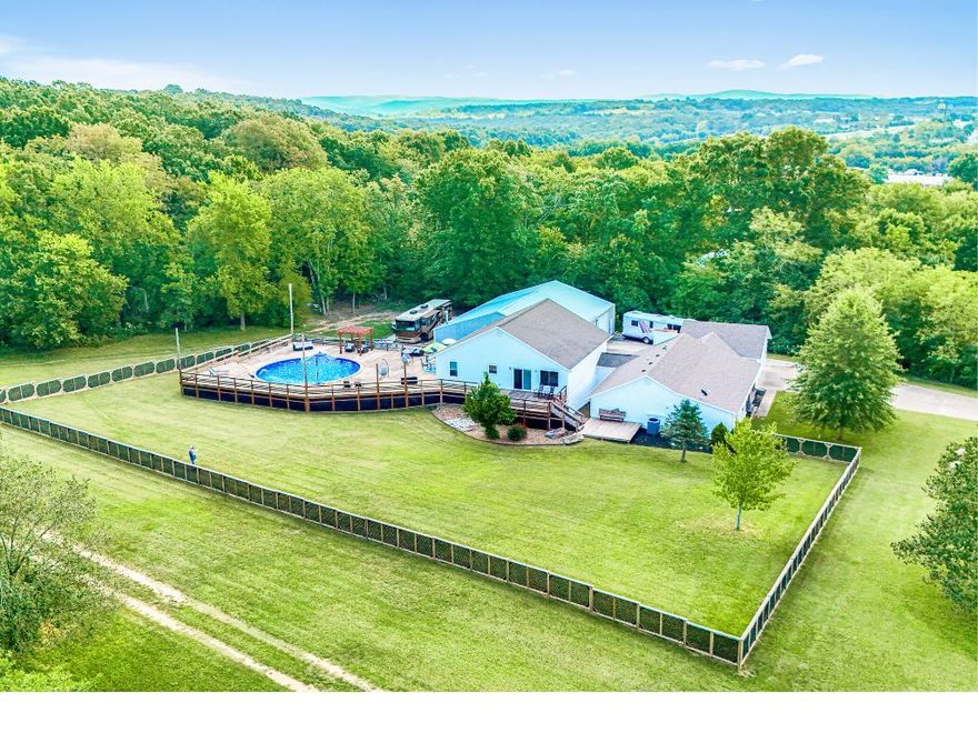 LIMITLESS OPTIONS FOR FAMILY, INVESTORS, AT HOME BIZ OR EVENTS AND 6 MINS TO THE UNIVERISTY OF ARKANSAS! This pristine land & unique tri-level home offers a heated pool & hot tub, sustainable green living w/ a geothermal HVAC system, all new Low-E windows, exterior security sys., brand-new roof and all newly updated appliances + multiple living spaces, 2 kitchens & laundry on each floor. Upper level has living area w/ dual-oven kitchen, 3 bed & 2 bath. Mid level has 3 bed, 3 bath, kitchenette + direct access to deck & pool. Lower level is ideal for entertaining or multi-gen living w/ tall ceilings, kitchen, theater, laundry & bath. Outdoor oasis w/ pool, wrap-around deck & hot tub. Perfect for relaxation & gatherings, the impressive theater room is perfect for game days & movie nights. This isn’t just a home, it’s an opportunity. A 2,400 sq. ft., 3-Bay, climate-controlled shop is a dream for a biz owner, car-enthusiast or artist w/ 10 ton car lift, compressed air plumbing, welding setup, 1/2 bath + pickleball court