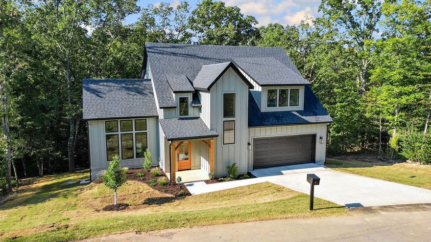Stunning new construction blends Mountain Modern style with natural materials and farmhouse warmth. This 4-bedroom, 2.5-bath, 2,340 sq ft home features tall ceilings, oversized windows, exposed beams, white oak flooring, modern finishes, and champagne bronze fixtures. The open-concept main floor flows effortlessly from the living area with gas fireplace to a dedicated dining space and kitchen with large island and stainless appliances—perfect for entertaining. The main-level primary suite offers a spa-like retreat with dual vanities, soaking tub, separate shower, and walk-in closet with washer/dryer connections. Upstairs, a bonus space, two bedrooms, a full bath, and second laundry add convenience. Step outside to the 154-sq ft covered back deck with gas connection and wrought iron railings ensuring an inviting space for relaxation. Located just 11 miles to the Walmart Home Office and downtown Bentonville, this home combines modern luxury with a peaceful, stylish retreat. Taxes are on lot only. Home is on SEWER!